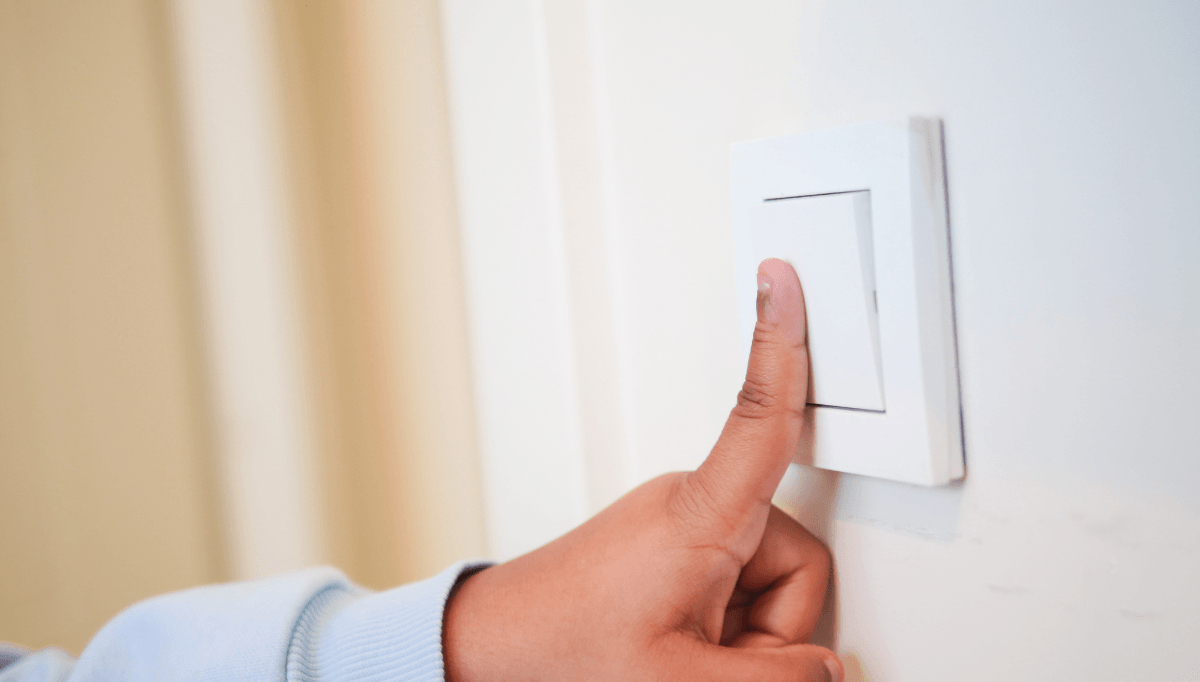 Child turning off a light switch to save energy at home
